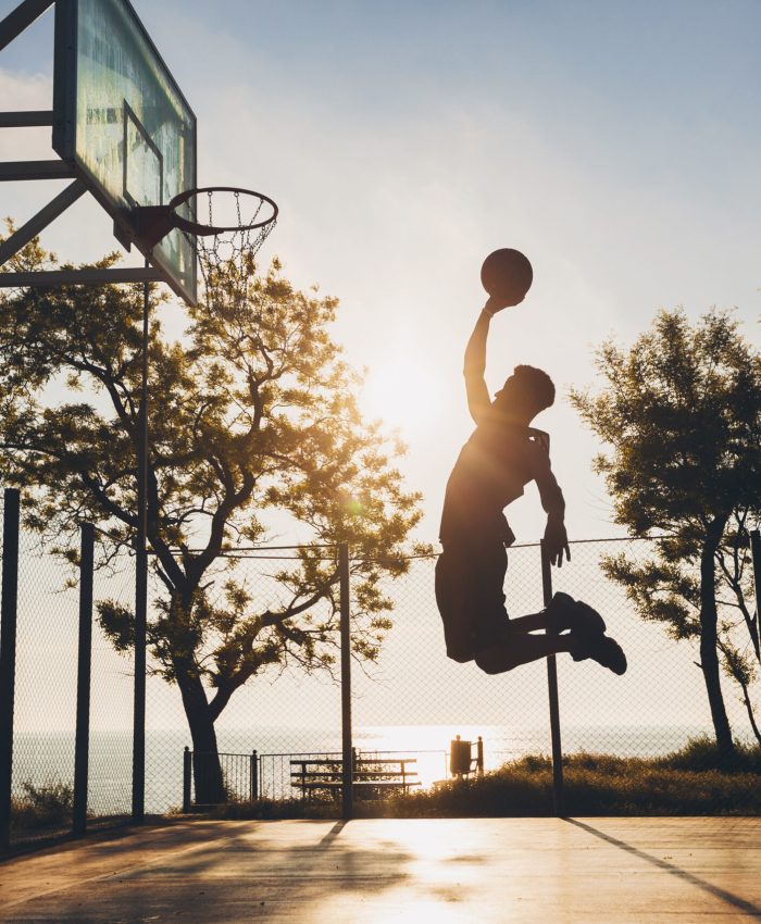 black man doing sports, playing basketball on sunrise, jumping silhouette